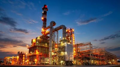 Industrielle Kraftwerksanlage mit beleuchteten Rohren bei D&auml;mmerung. | Copyright: KI-generiert by Ideogram