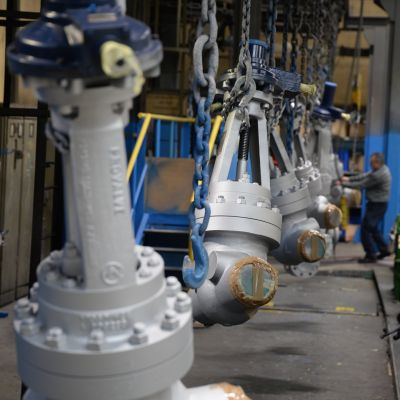 Mehrere graue Schieber mit verbolztem Deckel h&auml;ngen an Ketten in einer Industriehalle, bereit zur Montage oder zum Versand. | Copyright: PROVALVE Armaturen GmbH & Co. KG