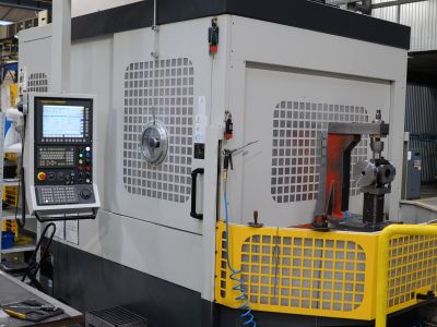 CNC-Bearbeitungszentrum in der Produktionshalle mit Bedienfeld, gelber Schutzvorrichtung und offener Maschinet&uuml;r. | Copyright: PROVALVE Armaturen GmbH & Co. KG